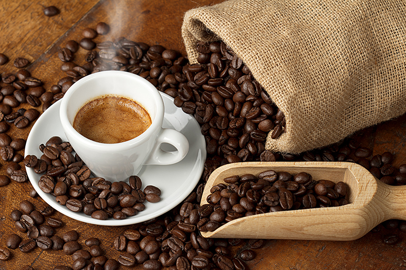 Café en grains dans un sac en toile de jute avec une tasse espresso